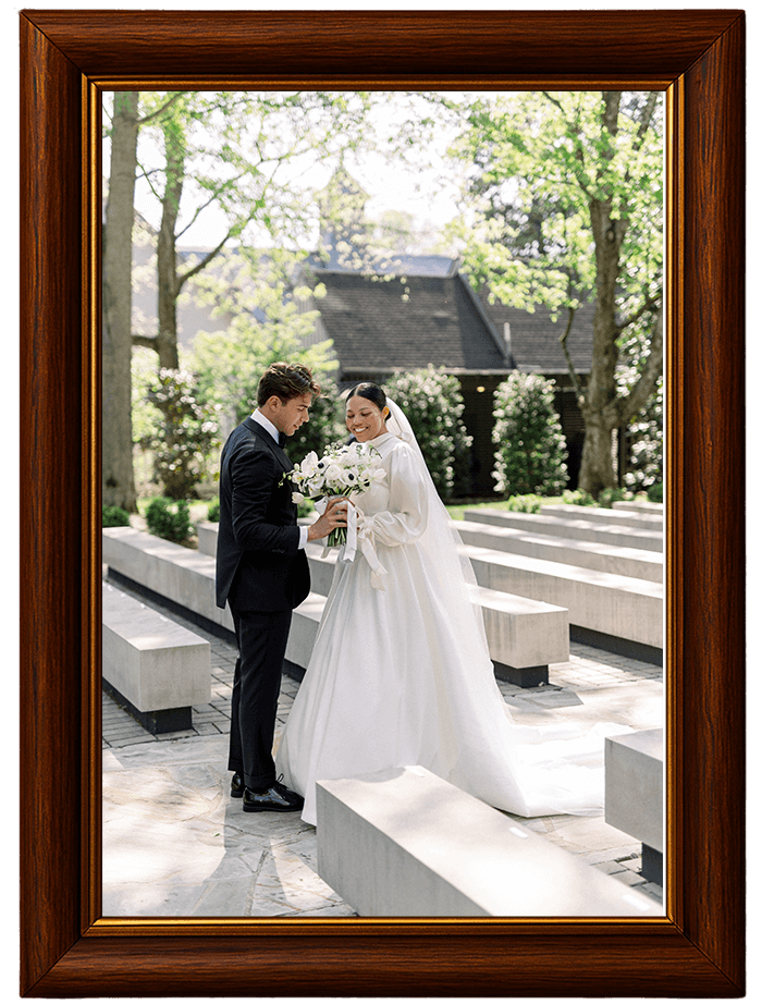 A bride and groom standing at an outside wedding venue between concrete benches